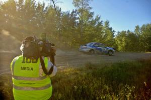 Piotr Wiktorczyk / Martin Brady are filmed by a local TV crewman on SS13 in their Subaru WRX.
