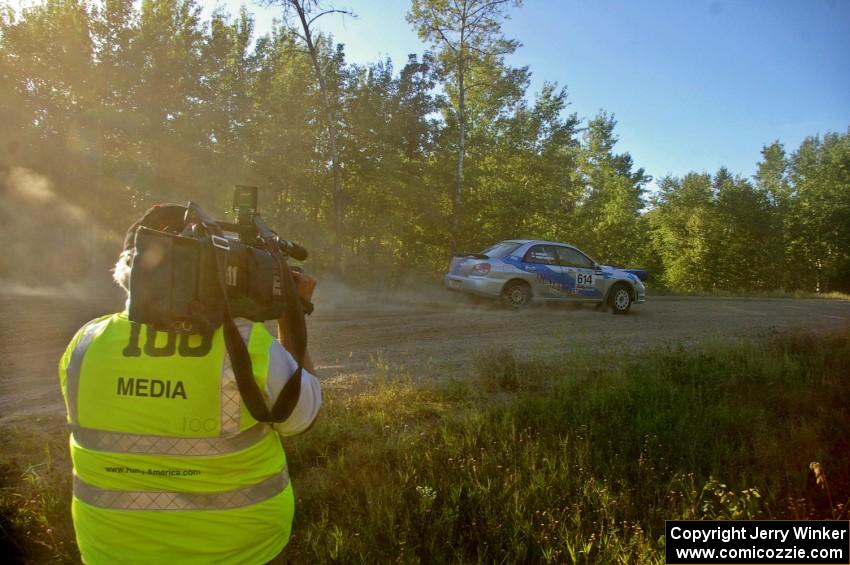 Piotr Wiktorczyk / Martin Brady are filmed by a local TV crewman on SS13 in their Subaru WRX.
