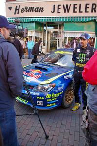 Alex Gelsomino is interviewed prior to the start of day two in front of the Ken Block Subaru WRX.