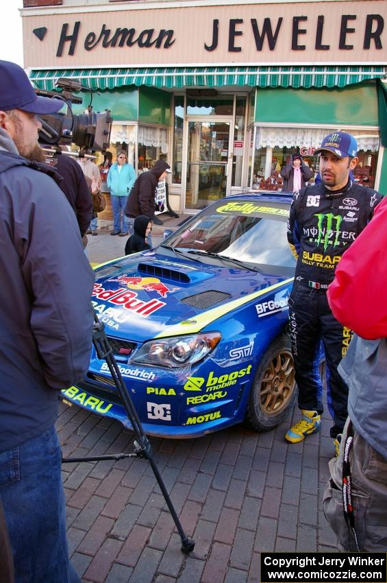 Alex Gelsomino is interviewed prior to the start of day two in front of the Ken Block Subaru WRX.