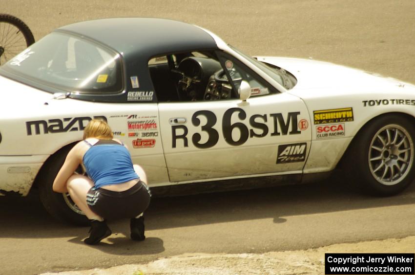 Samantha Silver checks the tires on her Spec Miata Mazda Miata