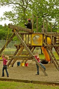 Kids play on the playground while a spotter watches the race from the top of the play structure