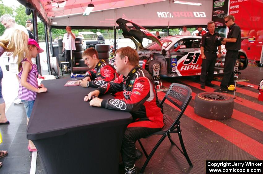 Dion von Moltke (L) and Jim Norman (R) sign autographs in front of their Audi R8.