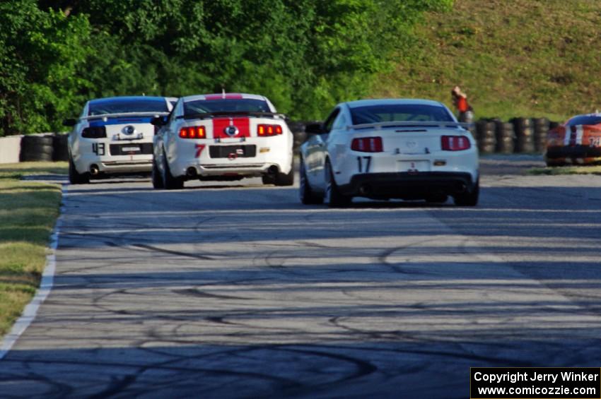 Three Ford Mustangs head into turn 7