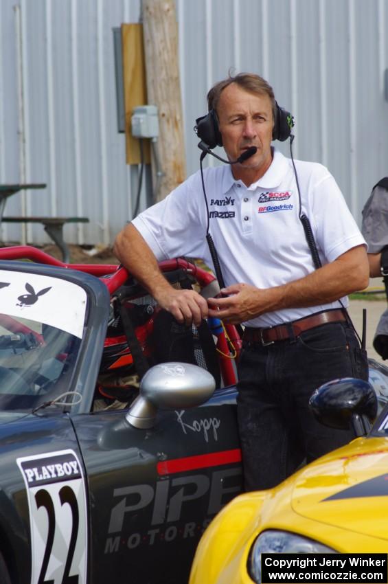 A series official leans against Kevin Kopp's Mazda MX-5