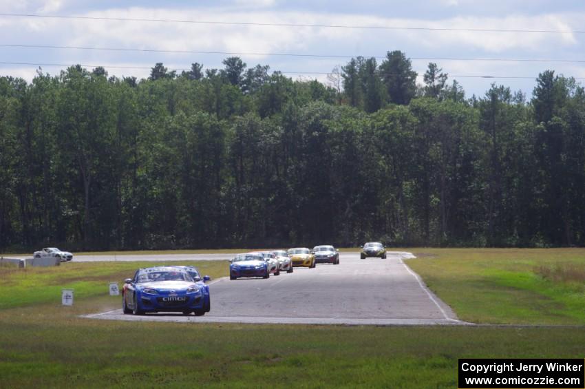 The Mazda MX-5 pack, fronted by Michael Cooper and Jason Saini, comes into turn 4 on lap three.