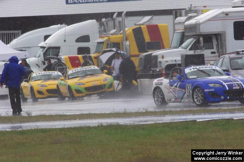 Jason Saini's Mazda MX-5 leaves the pits as Tim Probert and Ara Malkhassian get rain tires