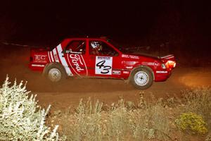 The Mike Whitman / Paula Gibeault Ford Sierra Cosworth at speed through the spectator corner at night.
