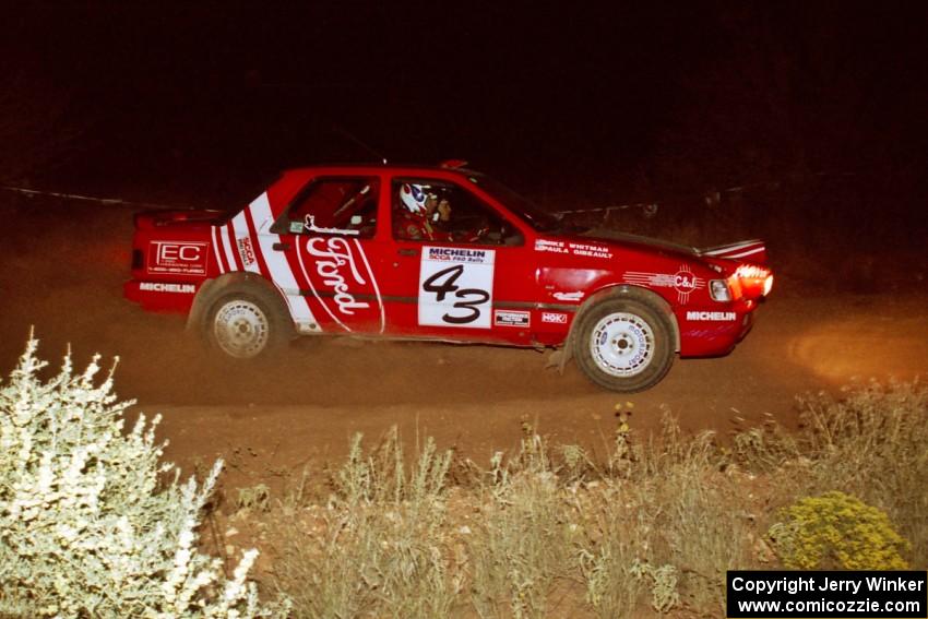 The Mike Whitman / Paula Gibeault Ford Sierra Cosworth at speed through the spectator corner at night.