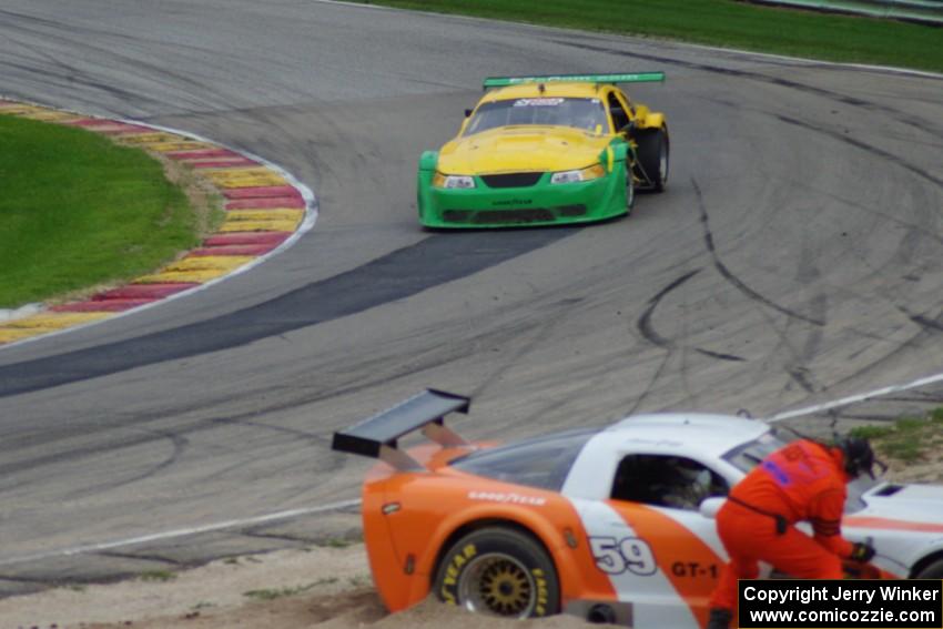 John Baucom's Ford Mustang passes as Simon Gregg's Chevy Corvette gets freed from the gravel trap