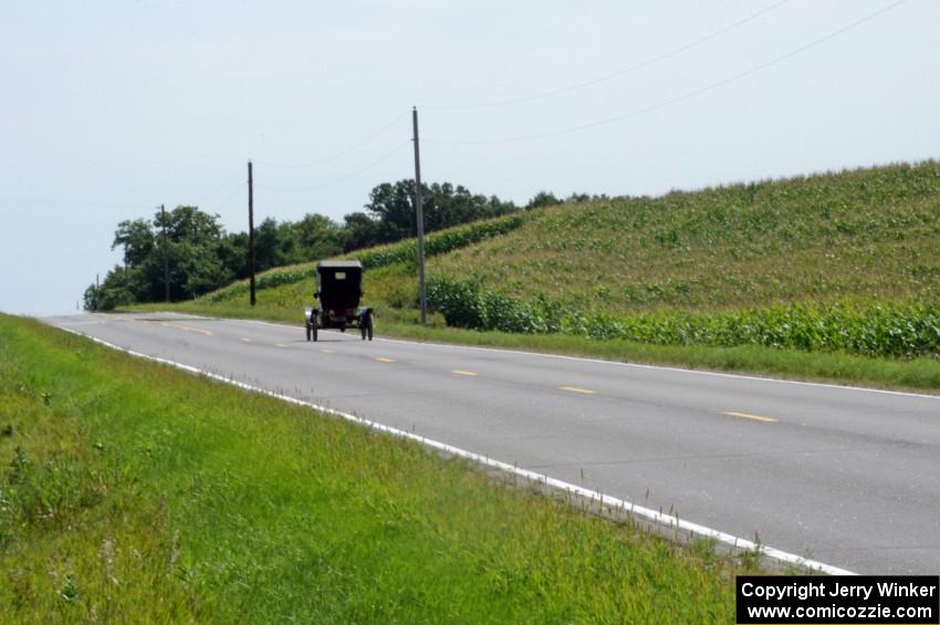 An unknown antique car putters across the Minnesota farmland