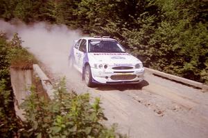Stig Blomqvist / Lance Smith Ford Escort Cosworth RS at speed over a bridge on SS5, Magalloway North.