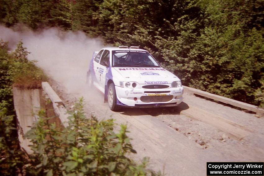 Stig Blomqvist / Lance Smith Ford Escort Cosworth RS at speed over a bridge on SS5, Magalloway North.