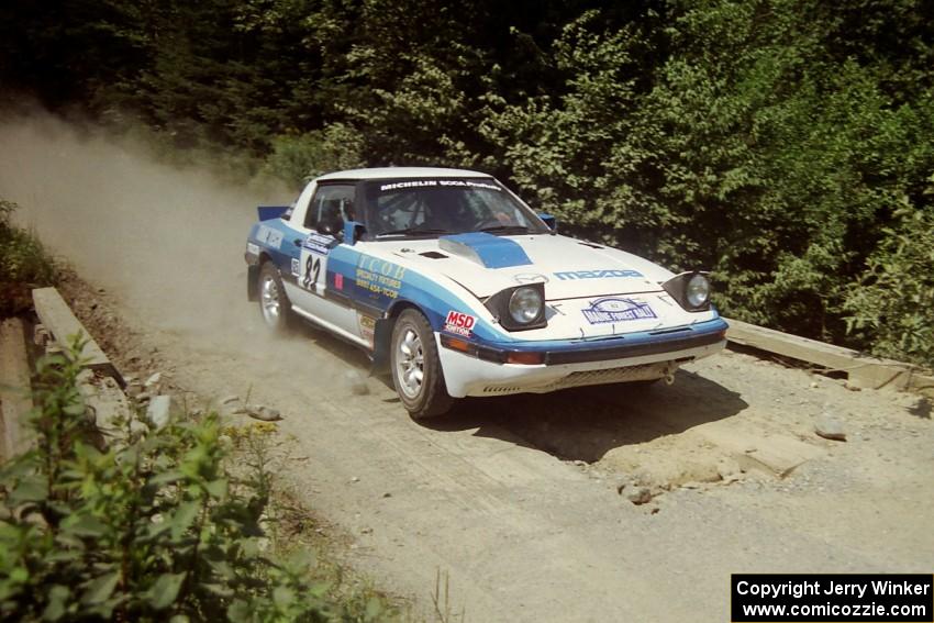 Mike Hurst / Rob Bohn Mazda RX-7 at speed over a bridge on SS5, Magalloway North.