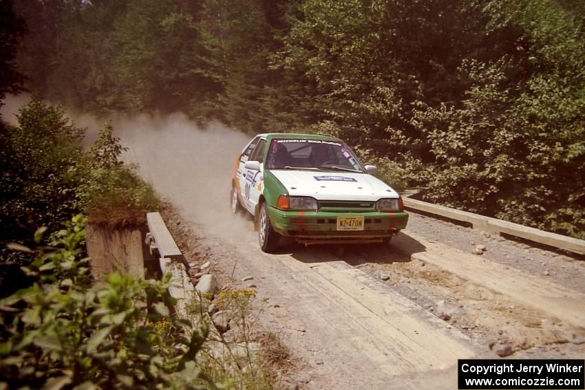 Donal Mulleady / John Reilly Mazda 323GTX at speed over a bridge on SS5, Magalloway North.