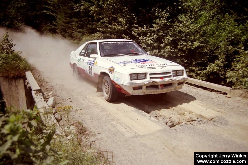 Lesley Suddard / Marc Goldfarb  Dodge Shelby Charger at speed over a bridge on SS5, Magalloway North.