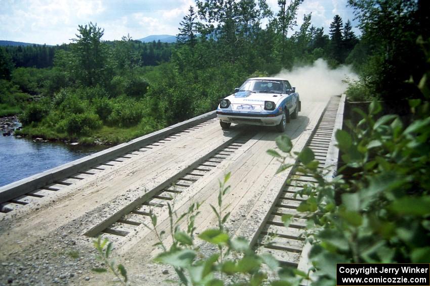 Mike Hurst / Rob Bohn Mazda RX-7 at speed over a bridge on SS8, Parmachenee Long.