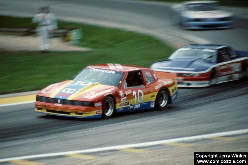 Don Sak's Olds Toronado ahead of Walter Payton's Olds Cutlass Supreme and Glenn Fox's Ford Mustang