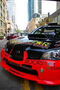 The Andy Pinker / Robbie Durant Subaru WRX STi parked directly under a skyway in front of the IDS Tower (1).