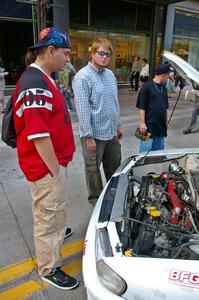 Ben Slocum explains rally to onlookers in front of the Kenny Bartram / Dennis Hotson Subaru Impreza L Coupe.