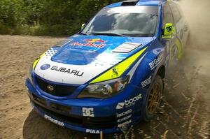 Travis Pastrana / Derek Ringer drifting rapidly past the apex of a corner on SS10 in their Subaru WRX STi.