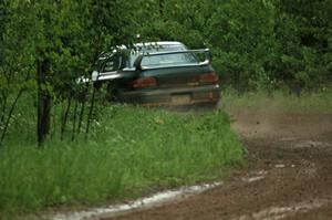 Janusz Topor / Michal Kaminski drift their Subaru Impreza through a left-sweeper on SS3 in the pouring rain.