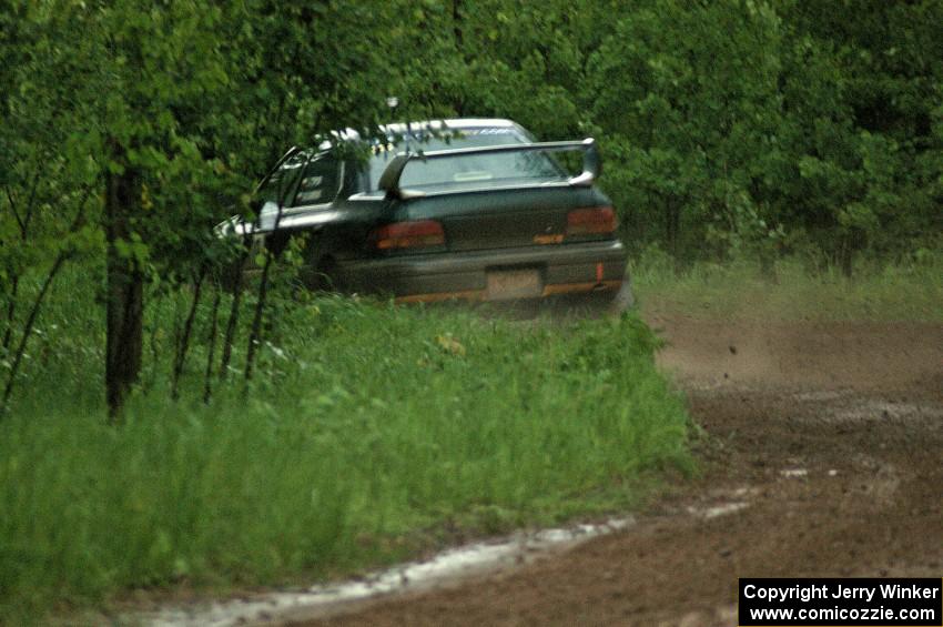 Janusz Topor / Michal Kaminski drift their Subaru Impreza through a left-sweeper on SS3 in the pouring rain.