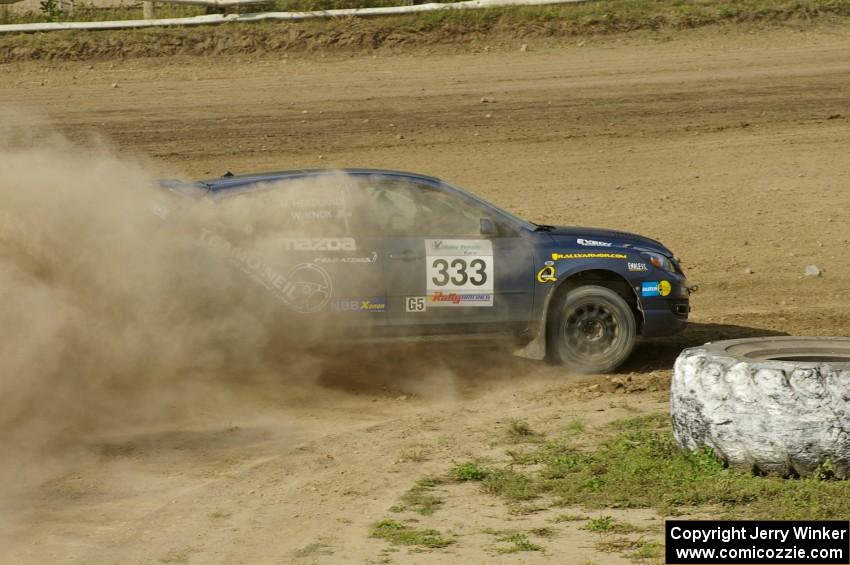 Wyatt Knox / Martin Headland drift their Mazda Speed 3 hard around a tractor tire on SS1.