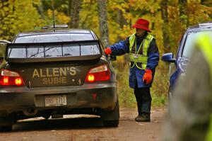 Barbara Steencken hands a time card to Vio Dobasu / Rob Amato in their Subaru WRX STi at the finish of Gratiot Lake, SS10.