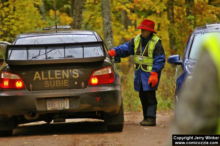 Barbara Steencken hands a time card to Vio Dobasu / Rob Amato in their Subaru WRX STi at the finish of Gratiot Lake, SS10.