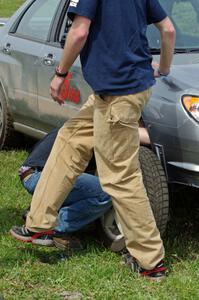 Dan Mooers changes the tire of his Subaru WRX on the course to get it off the track.