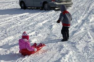 Kids pulling each other around in a sled in the spectator area.