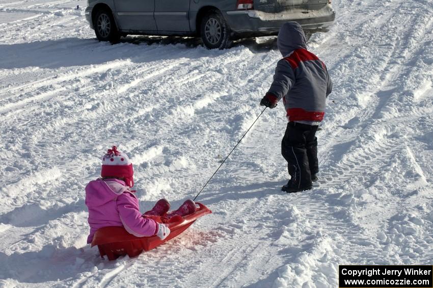 Kids pulling each other around in a sled in the spectator area.