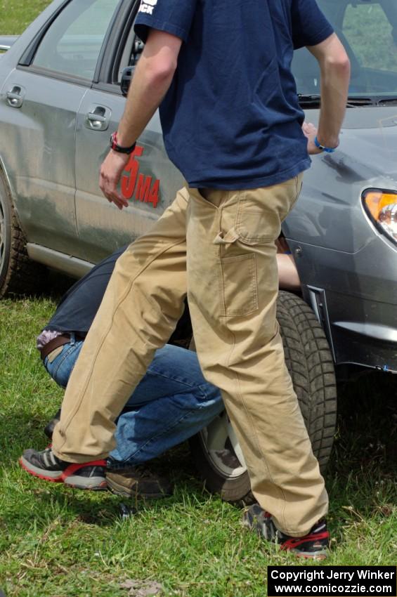 Dan Mooers changes the tire of his Subaru WRX on the course to get it off the track.