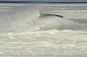 A car hits the powdery snow on the outside of a turn.