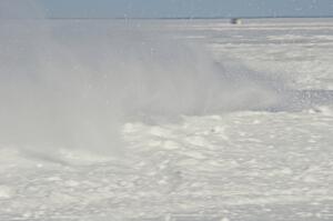 A car hits the powdery snow on the outside of a turn.