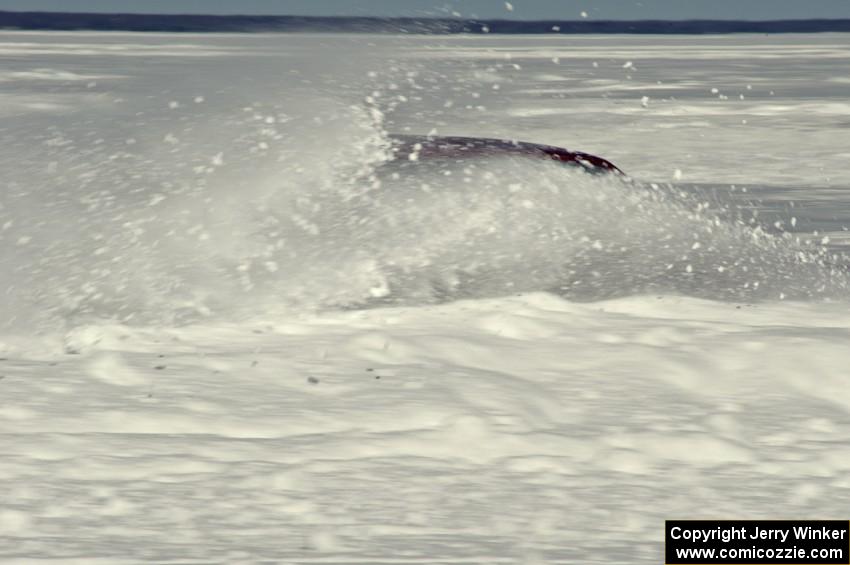 A car hits the powdery snow on the outside of a turn.