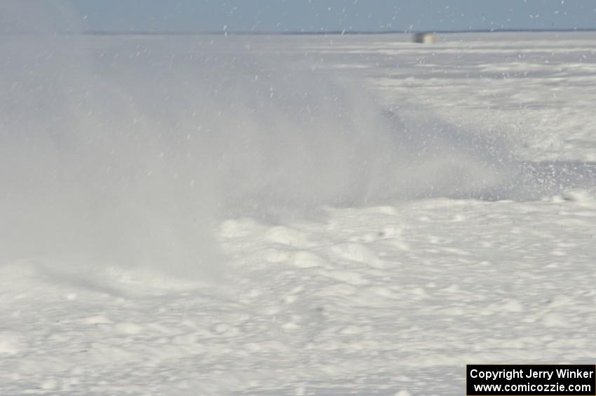 A car hits the powdery snow on the outside of a turn.