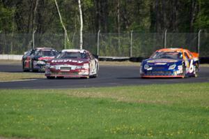 Cameron Hayley's Ford Fusion passes Derek Thorn's Ford Fusion while Michael Self's Chevy Impala follows.