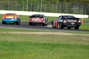 Cameron Hayley's Ford Fusion passes Derek Thorn's Ford Fusion while Michael Self's Chevy Impala follows.