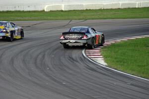 Michael Self's Chevy Impala passes Sergio Peña's Toyota Camry at turn 13.