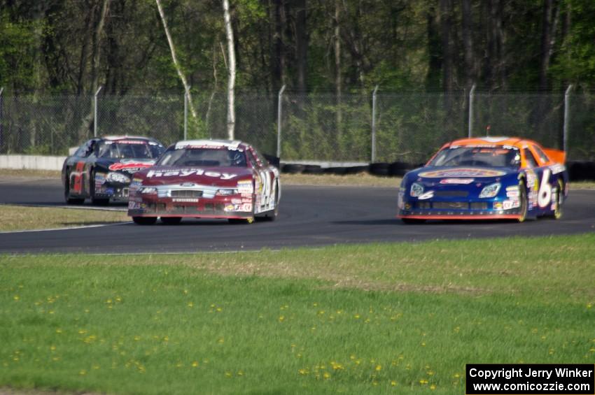Cameron Hayley's Ford Fusion passes Derek Thorn's Ford Fusion while Michael Self's Chevy Impala follows.