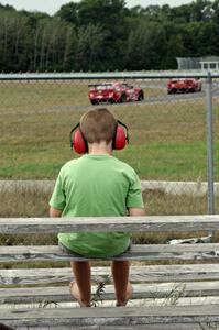 Pete Halsmer's Chevy Camaro chases Bob Stretch's Chevy Camaro as a young fan watches at turn 4.