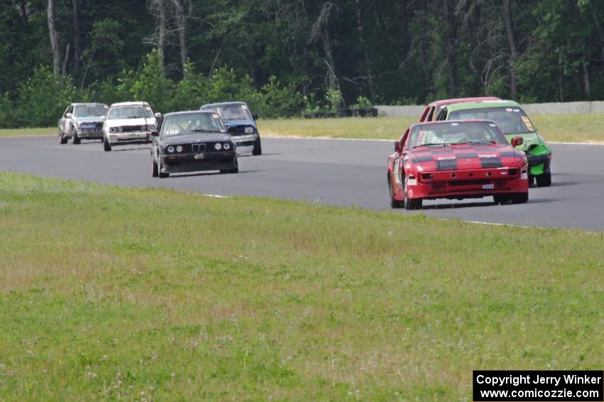 A stream of cars comes out of turn 3 into turn 4