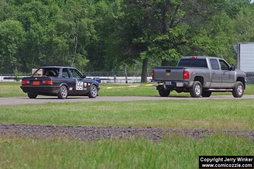 Cheap Shot Racing BMW 325is gets towed through the infield, back to the paddock.