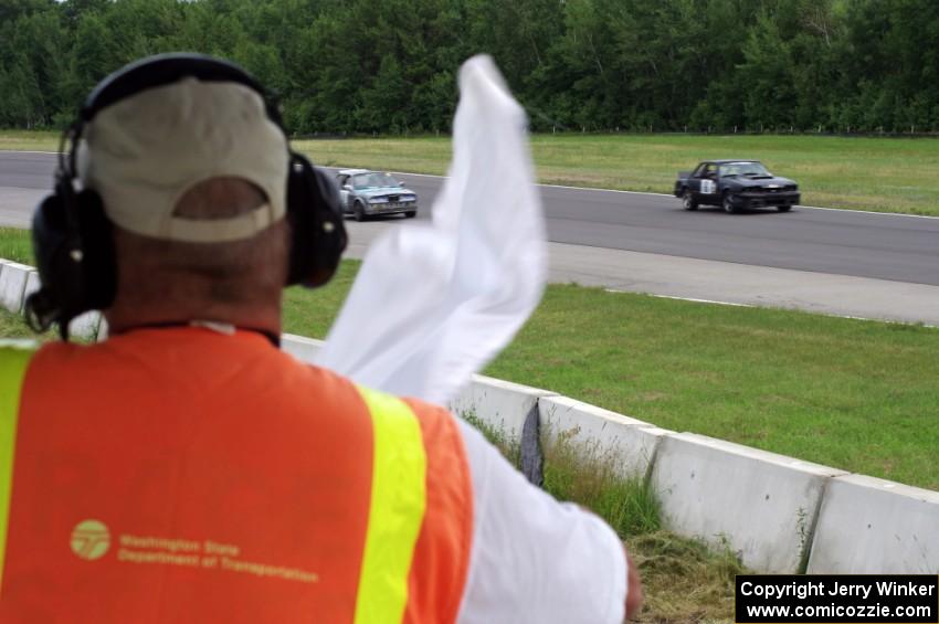 The white flag comes out at turn 2 as Wells Mafia Ford Mustang and Chump Faces BMW 325is pass by.