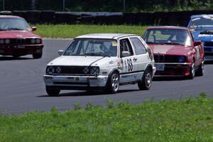 JAB Motorsport VW GTI and Missing Link Motorsport BMW 325 lead a pack through the carousel