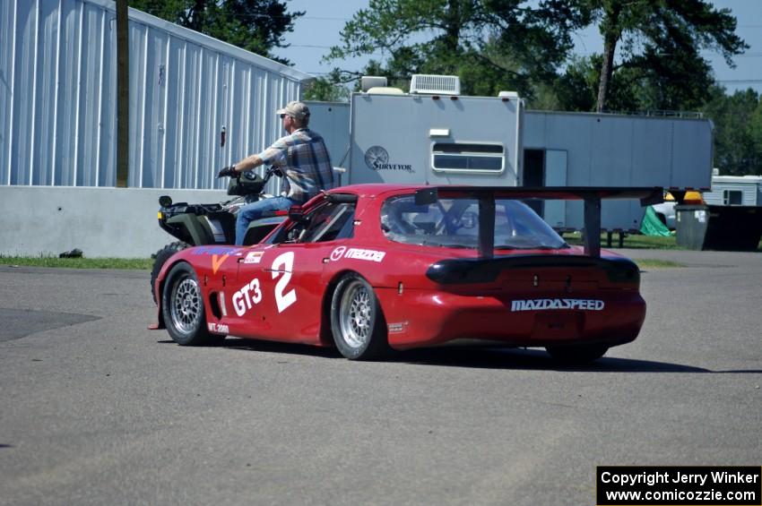 Doug Sherwood's GT-3 Mazda RX-7 gets pulled through the paddock