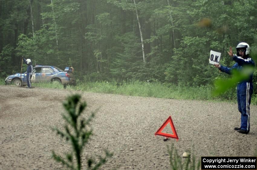 Dave Goodman displays the 'OK' sign while Carl Siegler waits to get his Subaru WRX STi freed from the berm.