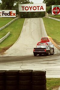 Mark Pluer's Ford Thunderbird trails a pack of cars headed uphill to turn 6.